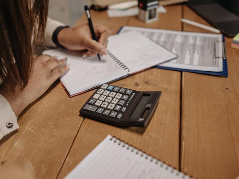Woman organizing financial documents and using a calculator at a desk